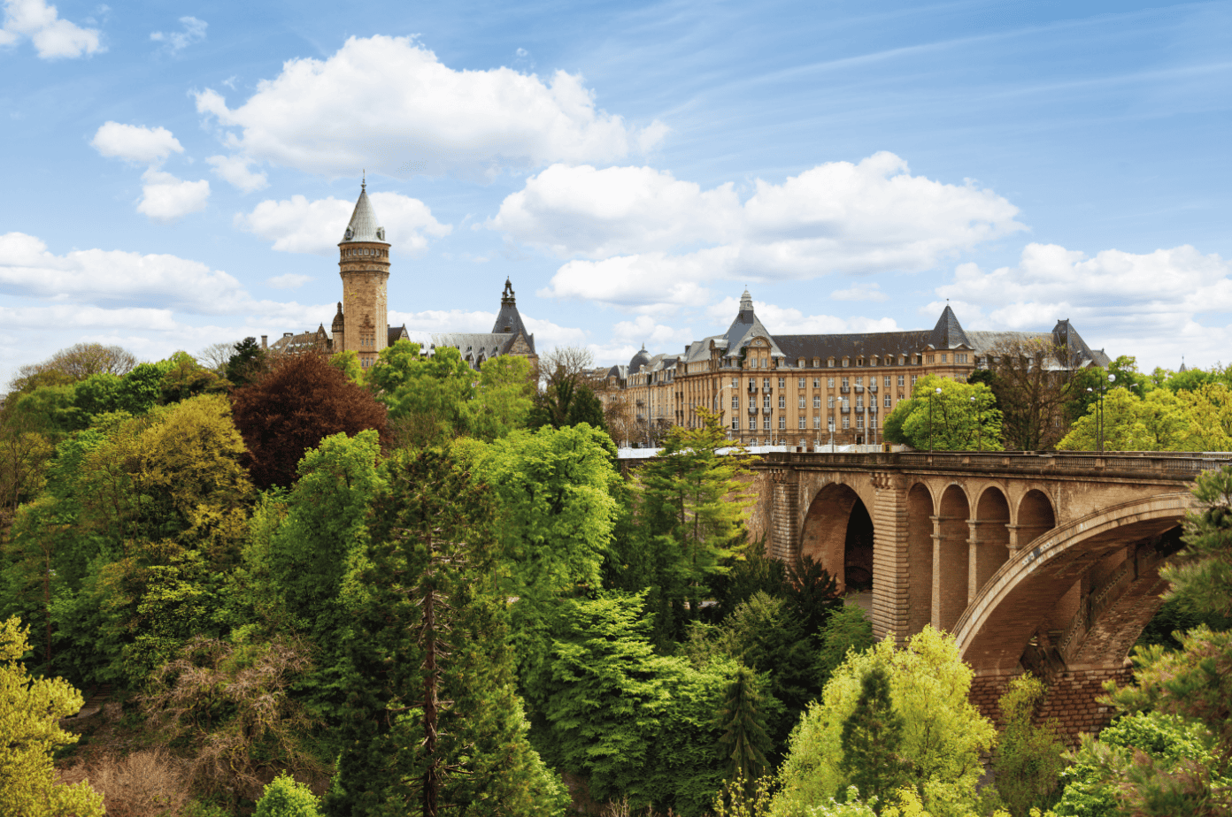 Alt: Panoramaaufnahme von Schloss Burg an einem sonnigen Tag, umgeben von grünen Bäumen im Frühling, ideal für Oldtimerwanderungen in Nordrhein-Westfalen.